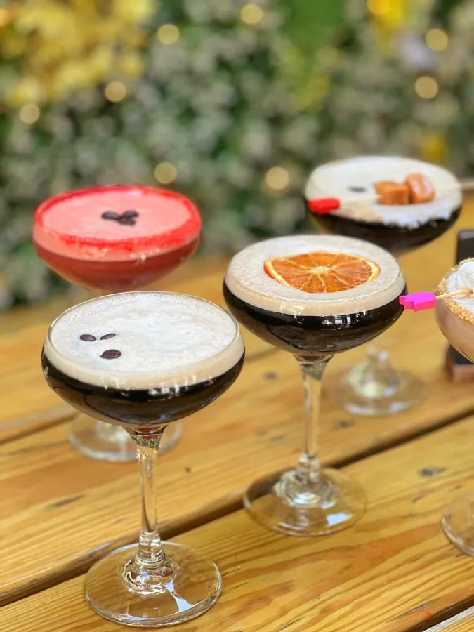 Three espresso martinis lined up on a wooden bar