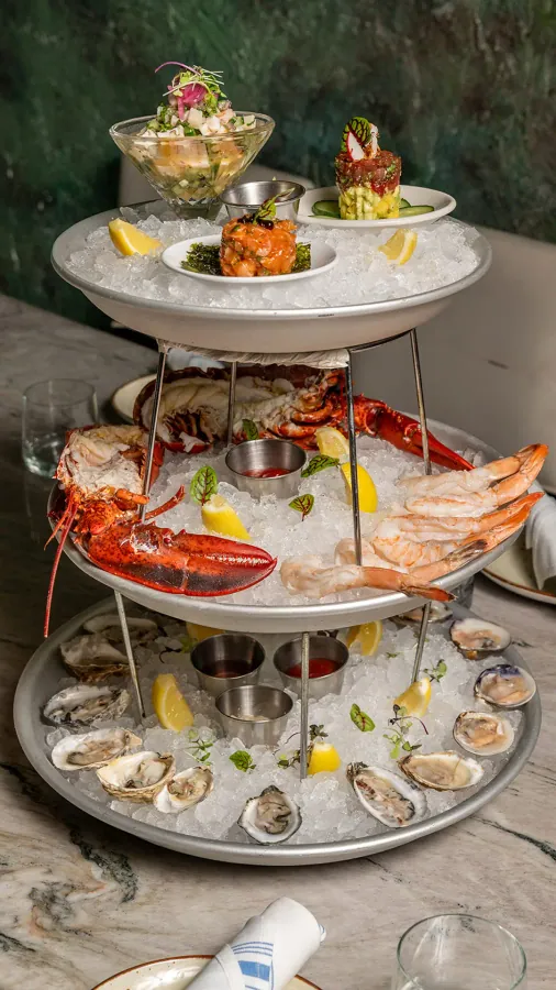 Tiered seafood tower with lobster, oysters and shrimp on ice