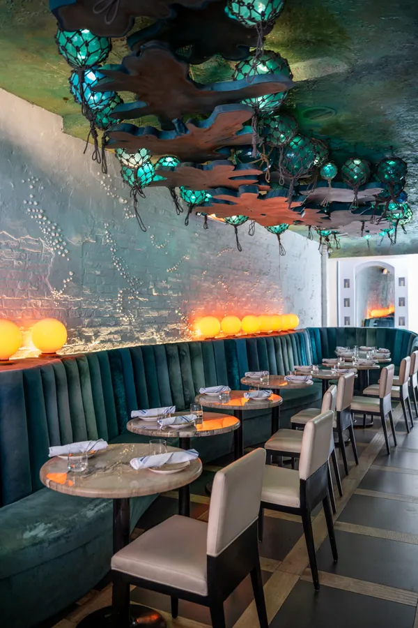 The dining room at Aquarelle, teal banquettes under glass-float lanterns
