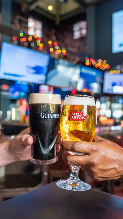 Two pints of beer clinking at a sports bar