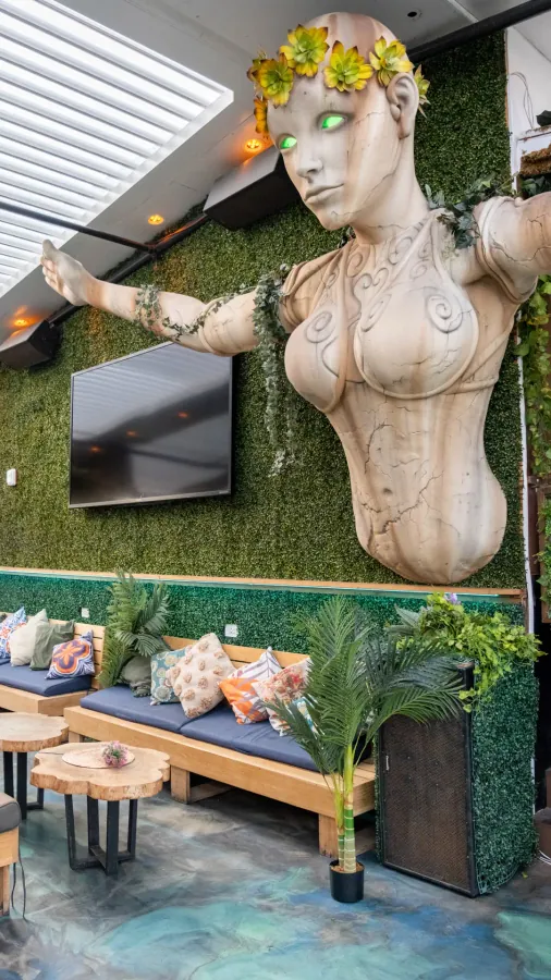 Outdoor lounge with a sculpture on a green wall