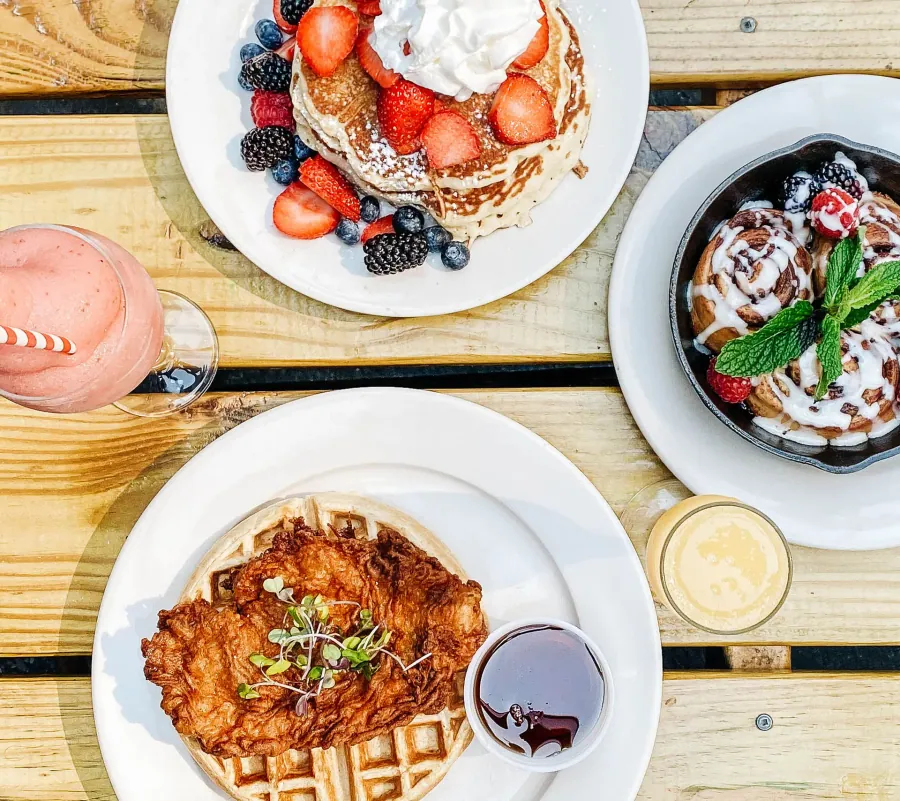 A full brunch table: pancakes, waffles and coffee, hands reaching in