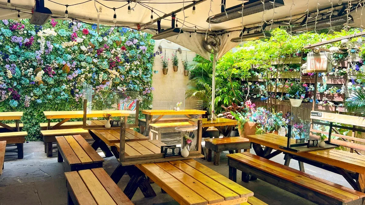 The beer garden at Loreley: picnic tables under string lights and a flower wall