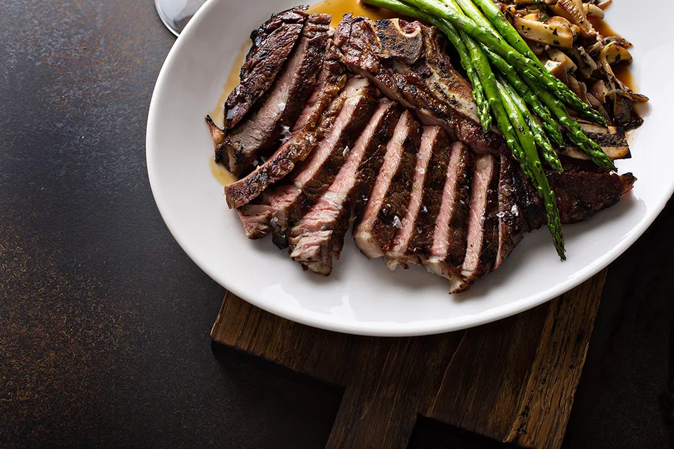 Sliced steak with asparagus on a white plate