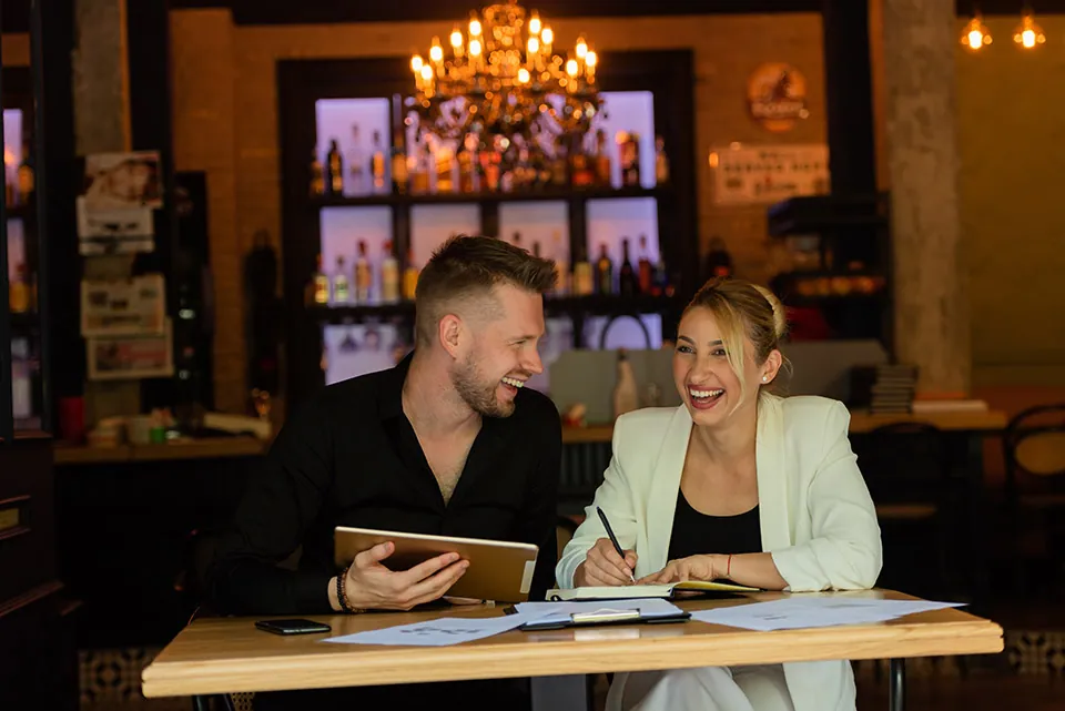 Two people reviewing content on a tablet in a cafe