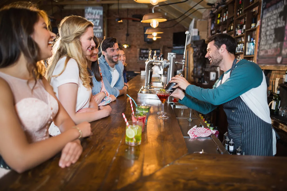Friends at a bar being served by the bartender