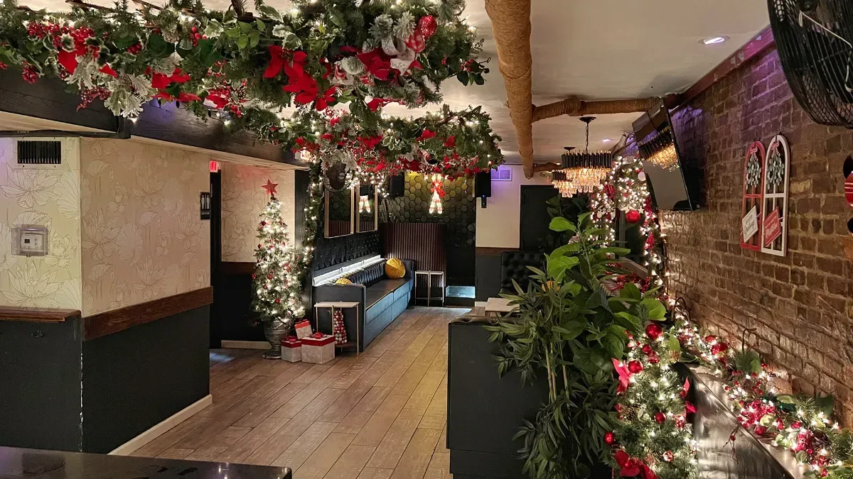 The lounge at Loreley Beer Garden dressed for the holidays, with garlands, red flowers, string lights and a small tree