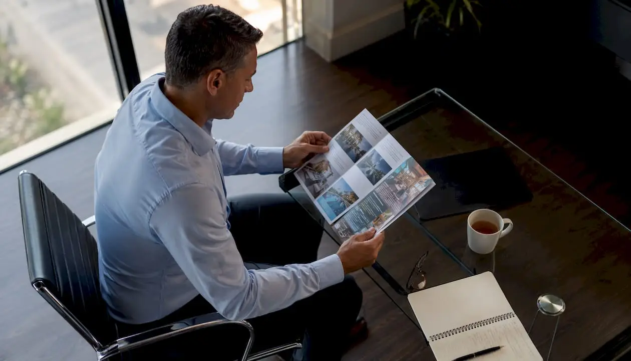 Restaurant owner reading magazine media kit at kitchen table