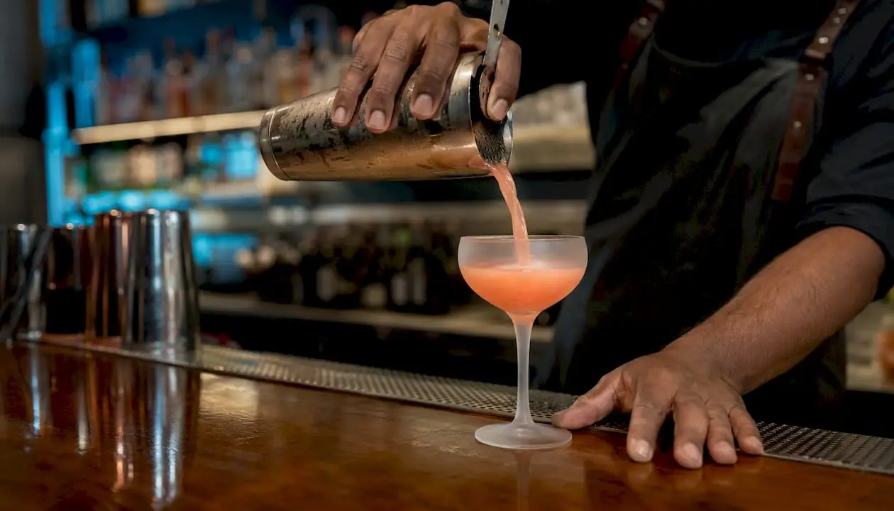 Bartender pouring cocktail into glass