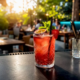 Pitcher of cocktail with glasses on bar